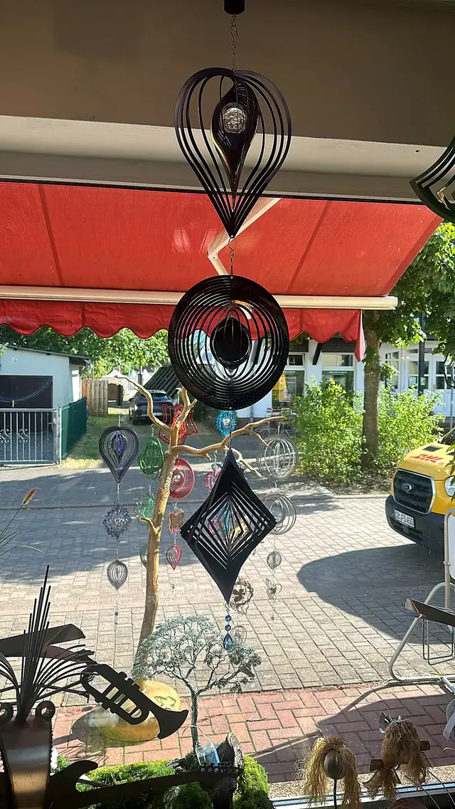 Schwarze Windspiele hängen im Schaufenster mit Blick auf die Straße